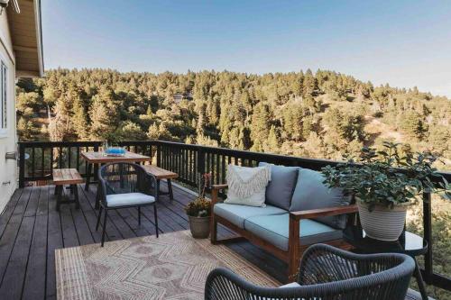 a patio with a couch and a table on a balcony at @wild_olive_den ~ Serene Weekend Getaway Cabin in Running Springs