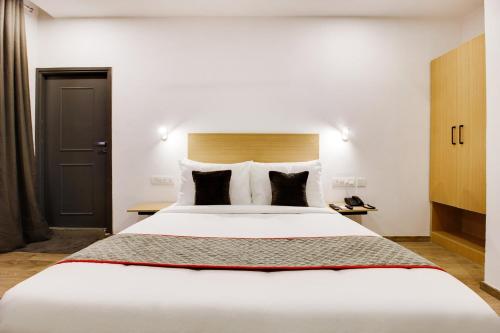 a bedroom with a large white bed with black pillows at Super townhouse moosapet Rcc Prime in Hyderabad