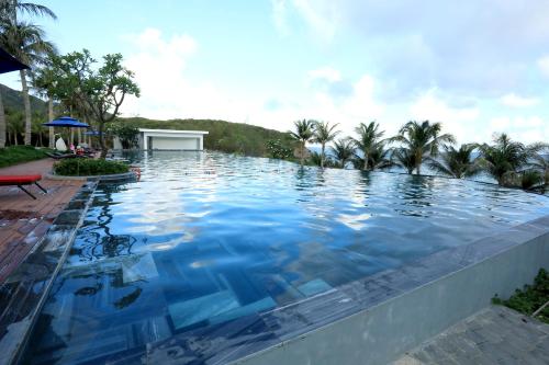 a swimming pool with blue water and palm trees at Orson Hotel & Resort Con Dao in Con Dao