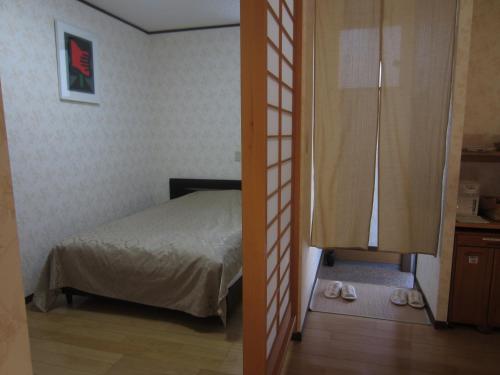 sypialnia z łóżkiem i drzwiami z kapciami w obiekcie 湯布院 おやど花の湯yufuin oyado hananoyu w mieście Yufu