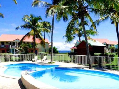 - une piscine bordée de palmiers dans une cour dans l'établissement Lullaby of the sea Crystal beach Saint François, à Saint-François