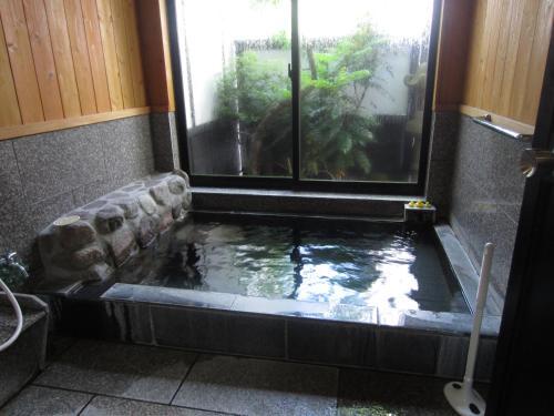 湯布院的住宿－湯布院 おやど花の湯yufuin oyado hananoyu，窗户浴室里的鱼塘