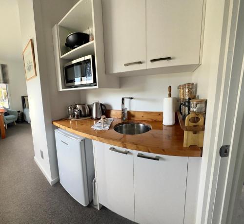 eine Küche mit weißen Schränken und einer hölzernen Arbeitsplatte in der Unterkunft Envisage Estate in Cambridge