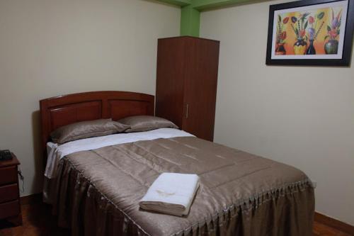 a bedroom with a large bed with a wooden headboard at HOTEL LUCERO REAL in Tacna