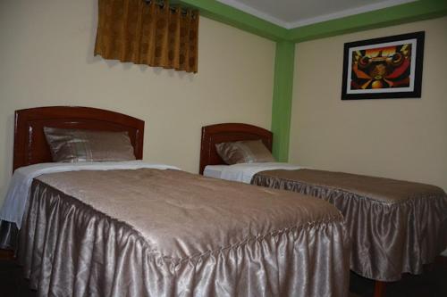 two beds in a room with green walls at HOTEL LUCERO REAL in Tacna