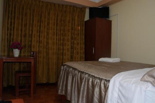 a bedroom with a bed and a dresser and a table at HOTEL LUCERO REAL in Tacna