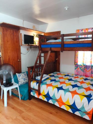 a bedroom with two bunk beds and a chair at Puerto Galera Transient Kubo Guest Place in Puerto Galera