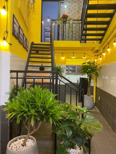 a lobby with potted plants and a yellow staircase at Ga Homestay in Hai Phong