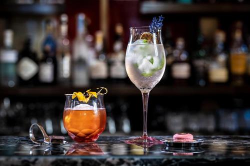 two cocktails sitting on a bar with a drink at Augustine, a Luxury Collection Hotel, Prague in Prague
