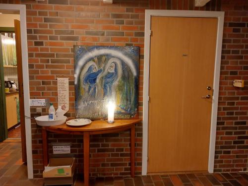 a candle on a table next to a wall with a painting at Station im Norden in Bindslev