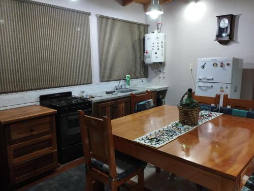 cocina con mesa de madera, fregadero y fogones en La Lechuza hospedaje en Salta