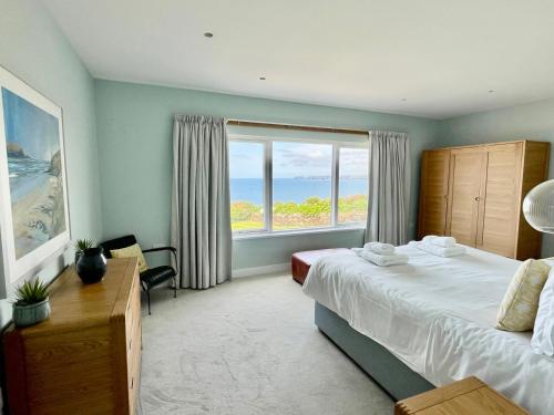 a bedroom with a bed and a large window at The Old Coastguard Lookout in Port Isaac