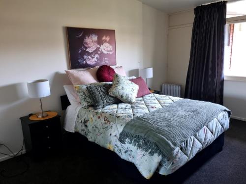 a bedroom with a bed with pillows on it at Home Away from Home - Waitaki Lakes Apartment A5 in Otematata