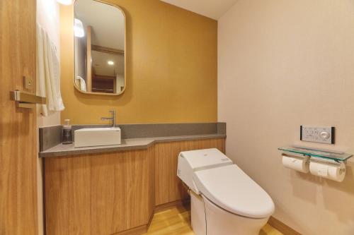 a bathroom with a toilet and a sink and a mirror at Miyako Hotel Kyoto Hachijo in Kyoto