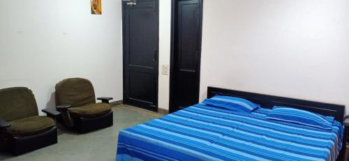 - une chambre avec un lit et deux chaises dans l'établissement Blessings Noida Home stay, à Noida
