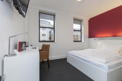 1 dormitorio con 1 cama, escritorio y 2 ventanas en mk hotel london en Londres