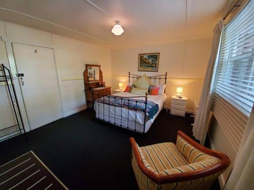 a bedroom with a bed and a chair and a window at Historic Apartment in Oatlands