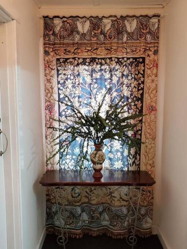 a vase on a table in front of a window at Historic Apartment in Oatlands