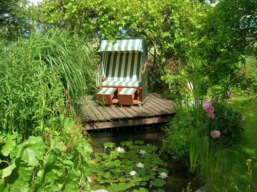 a chair sitting on a wooden bridge over a pond at Hof Garz in Poseritz