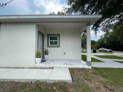 une petite maison blanche avec une véranda et une allée. dans l'établissement 3BD/2BTH Home Near Downtown Orlando, à Orlando
