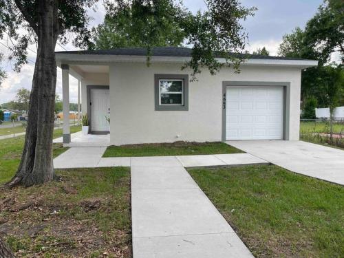 ein weißes Haus mit einer Garage und einem Baum in der Unterkunft 3BD/2BTH Home Near Downtown Orlando in Orlando