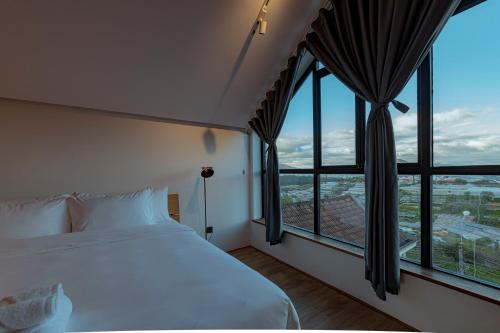a bedroom with a white bed and large windows at La Villa Da Lat in Khu Chi Lăng