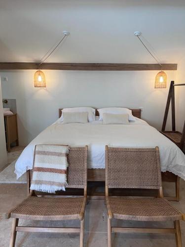 une chambre avec un grand lit blanc avec deux chaises dans l'établissement L’oliveraie, à Ventenac-Cabardès