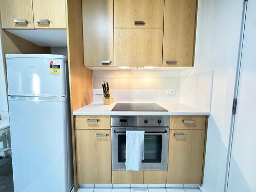 a kitchen with a stove and a refrigerator at Cozy 1-bedroom unit at CBD in Auckland