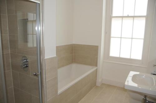 a bathroom with a shower and a tub and a sink at Beaufort House Apartments from Your Stay Bristol in Bristol
