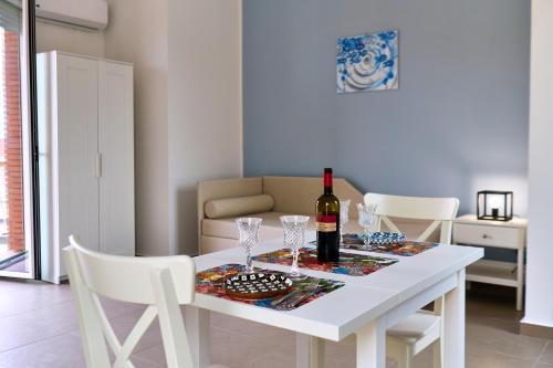 a white table with a bottle of wine and glasses at Vento di Mare in Piraino