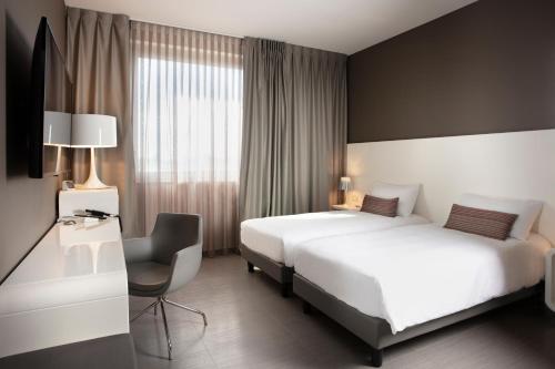 a hotel room with two beds and a desk at 8Piuhotel in Lecce