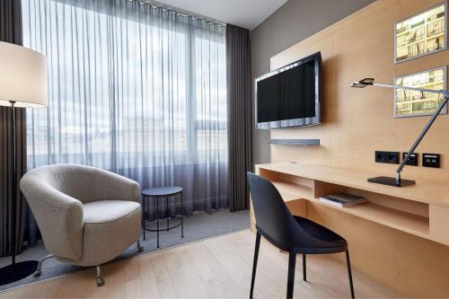 a hotel room with a desk and a chair and a television at Le Méridien Vienna in Vienna