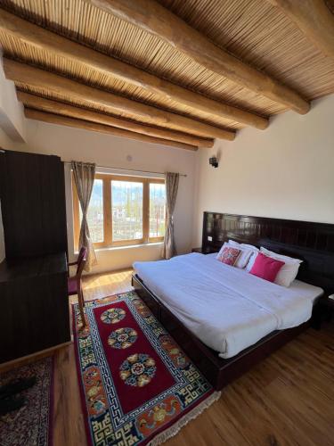 a bedroom with a large bed and a large window at Heschuk Guest House in Leh
