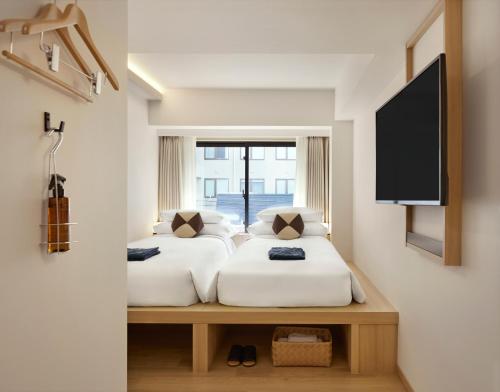 two beds in a room with a window at ASAI Kyoto Shijo in Kyoto