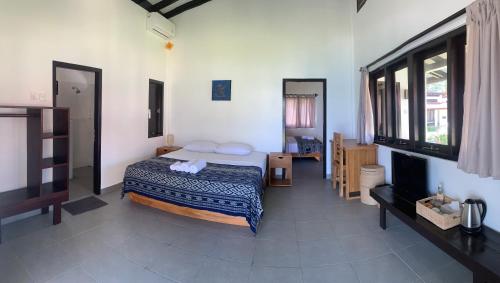 sypialnia z łóżkiem i telewizorem w obiekcie Balong Balong Surf Bungalows & Restaurant w mieście Sekongkang