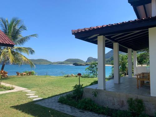 a house with a table and a view of the water at Balong Balong Surf Bungalows & Restaurant in Sekongkang