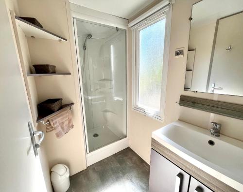 baño blanco con ducha y lavamanos en Camping Des Mimosas, en Argelès-sur-Mer