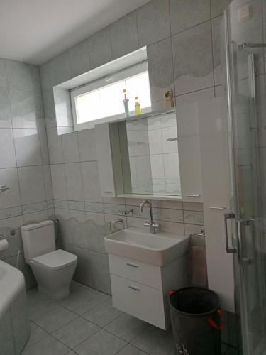 uma casa de banho com um lavatório, um WC e uma janela. em Apartman Laguna em Balatonlelle