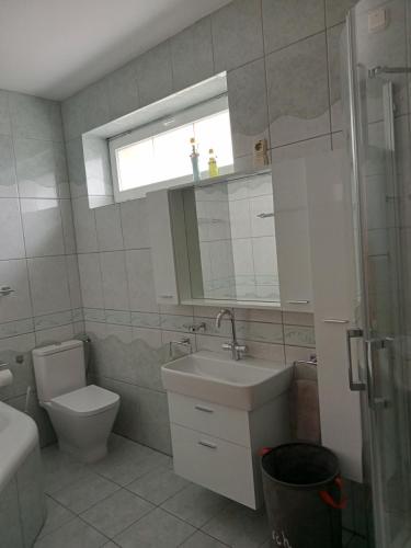 a bathroom with a sink and a toilet and a window at Apartman Laguna in Balatonlelle