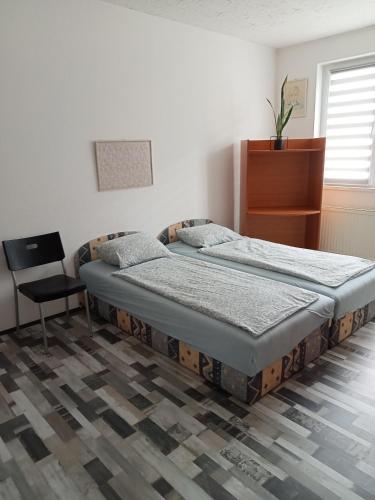 um quarto com uma cama e uma cadeira em Apartman Laguna em Balatonlelle