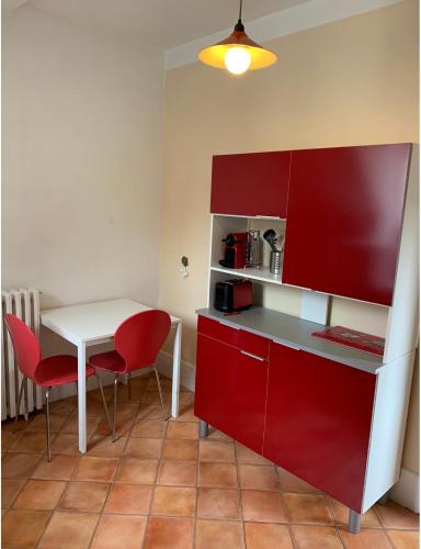 une cuisine avec des armoires rouges et une table et des chaises dans l'établissement maison delalonde Autun centre charmant meublé 5 places, à Autun