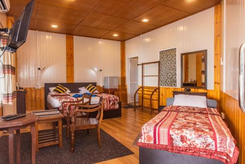 a bedroom with two beds and a desk and a table at Ravana Range Ella in Ella