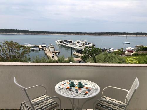 a table and chairs on a balcony with a view of a harbor at Apartments Aco in Barbat na Rabu