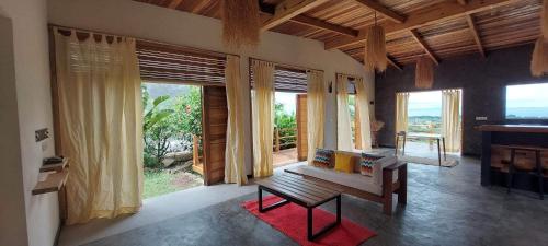 a living room with a bench and large windows at RESIDENCE TSARA BE in Nosy Be