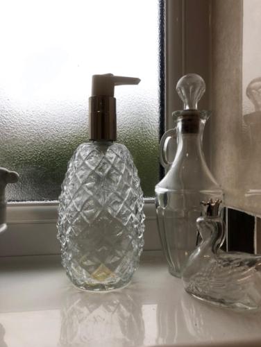 two glass bottles sitting on a counter next to a window at Budget London Room in London