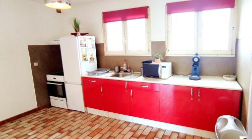 une cuisine avec des armoires rouges et un réfrigérateur blanc dans l'établissement Grand bas de villa au calme faux 3 pièces de 63 m, à La Valette-du-Var