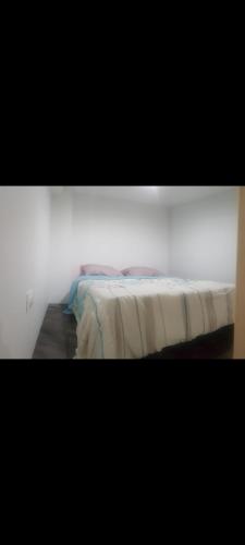 łóżko w pokoju z białą ścianą w obiekcie Charmant studio w mieście La Verrière
