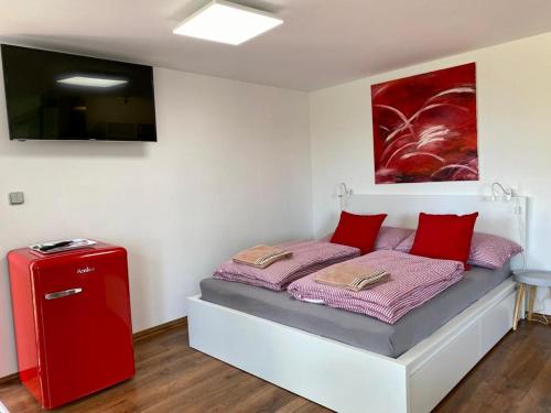 a bedroom with a bed with red pillows and a red refrigerator at Apartmán - E - Vyhlídka nad řekou in Zdiby