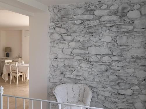 een stenen muur met een witte stoel in een kamer bij APE BIANCA - Appartamento Lavanda in Colico