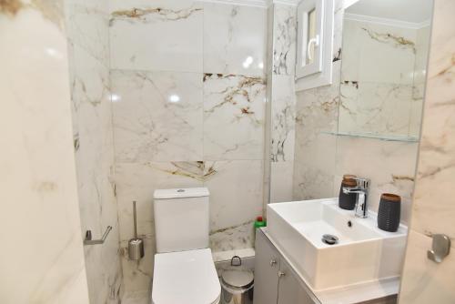 a white bathroom with a toilet and a sink at No15 central apartment in Kavala